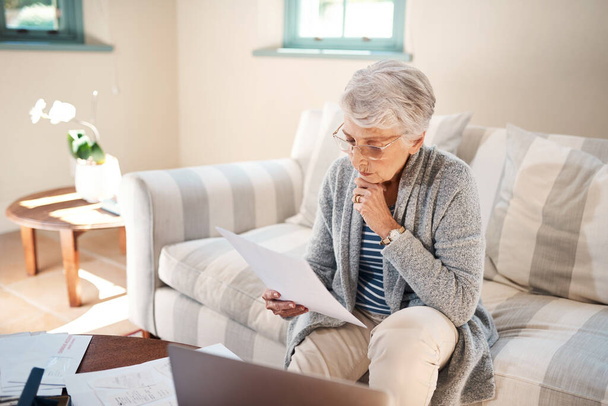 Is this worth investing in. a senior woman going through paperwork at home - Photo, Image