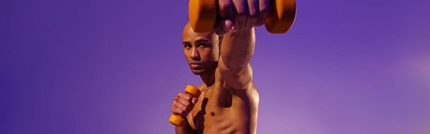 Мускулистый человек делает упражнения с гантелями веса на фоне студии с цветным фильтром - Фото, изображение