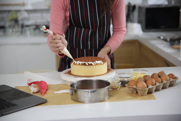 Азиатская домохозяйка готовит выпечку или пирог на кухне дома - Фото, изображение
