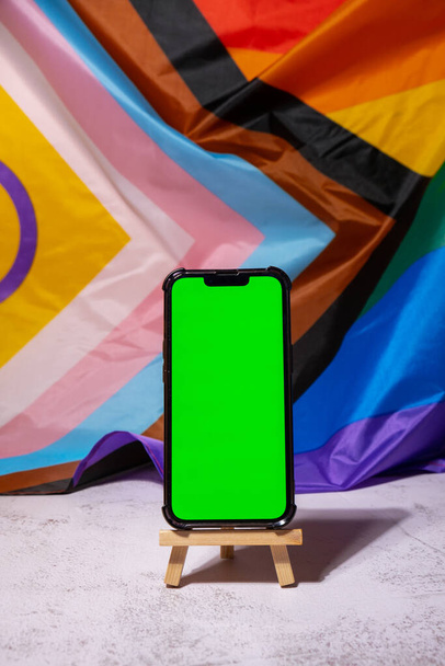 Mobile phone with chroma key on Rainbow LGBTQIA flag made from silk material background. Happy pride month. Symbol of LGBTQ pride month. Equal rights. Peace and freedom. Support LGBTQIA community - Foto, Bild