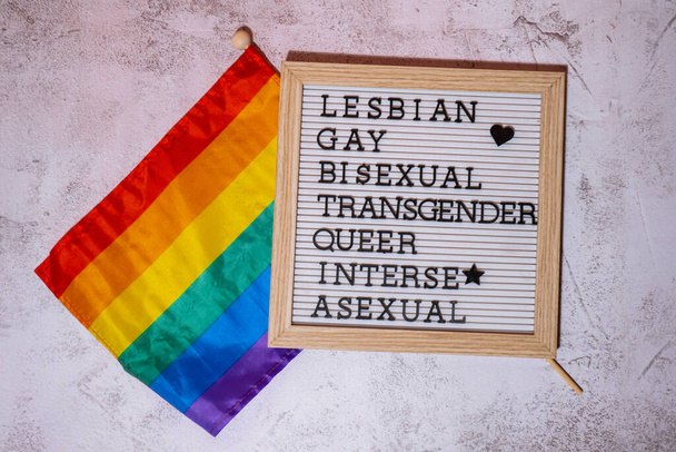 LGBTQIA description frame on Rainbow LGBTQIA flag made from silk material. LESBIAN, GAY, BISEXUAL, TRANSGENDER, QUEER, INTERSEX, ASEXUAL. Symbol of LGBTQ pride month. Equal rights. Peace and freedom - 写真・画像