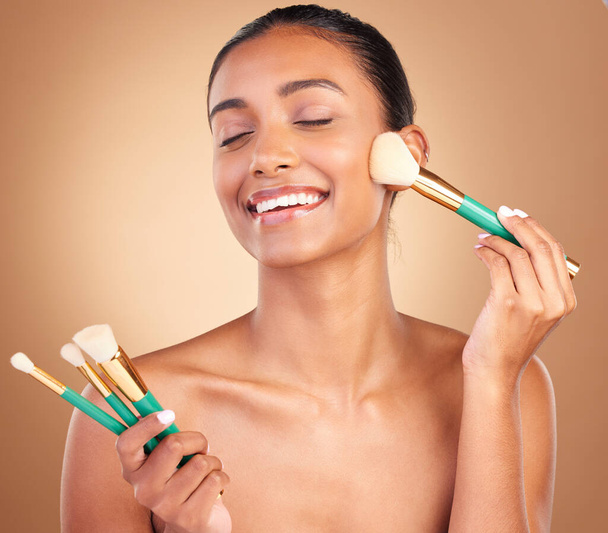 Makeup brushes, smile and woman with natural beauty, wellness and happiness from cosmetics. Facial skin glow, happy and cosmetic artist brush of a young female model with self care in a studio. - Photo, image