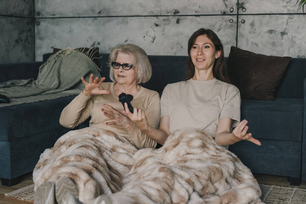 Millennial starší žena hraje video hry držení ovladač, zatímco vzrušený emocionální dcera gestikuluje sedí na podlaze doma, šťastní teenageři baví - Fotografie, Obrázek