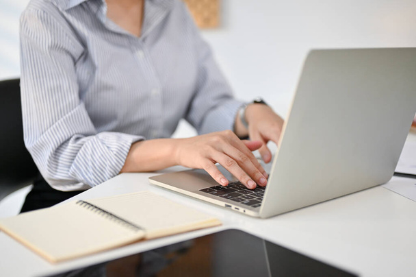 Cropped image of a professional businesswoman or female office worker using her laptop at her desk, typing on keyboard, working on online tasks. - Fotó, kép