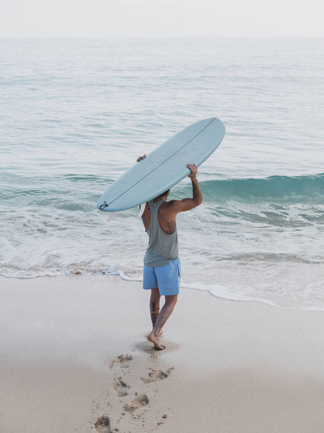 Nierozpoznany surfer z tyłu na brzegu plaży - Zdjęcie, obraz