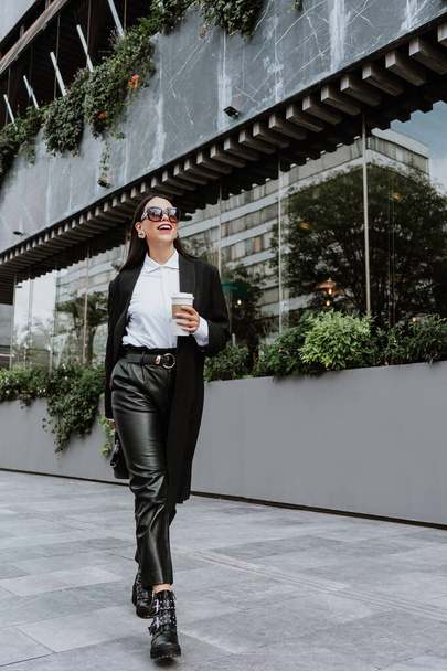 joven mujer latina de negocios caminando por la calle sosteniendo café y mirando hacia los lados en la ciudad de México, mujer hispana - Foto, imagen