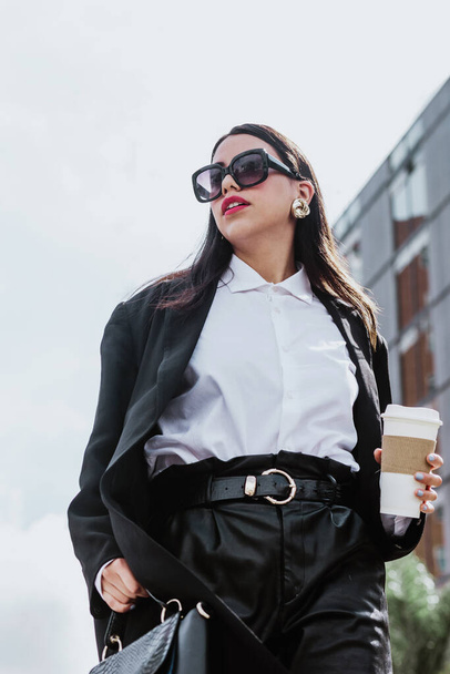 giovane donna d'affari latina che cammina per strada tenendo il caffè e guardando lateralmente a Città del Messico, donna ispanica - Foto, immagini