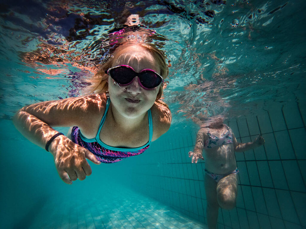 A talented young girl swimmer dives into a full-size tournament pool to train or compete.  - Foto, immagini
