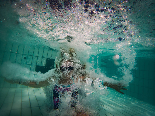 A talented young girl swimmer dives into a full-size tournament pool to train or compete.  - Фото, зображення
