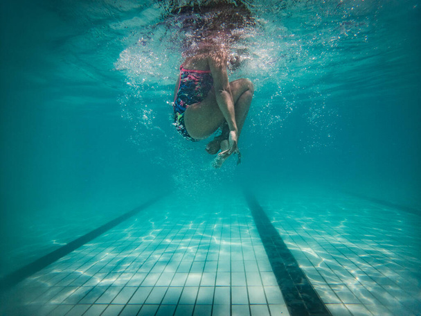 Una talentosa nadadora se sumerge en un grupo de torneos de tamaño completo para entrenar o competir.  - Foto, imagen