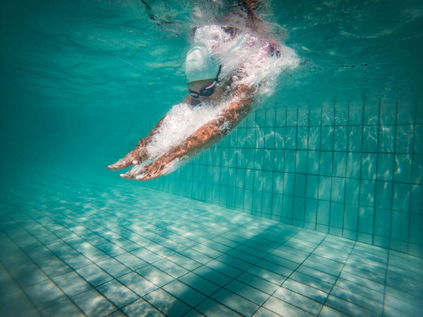 A talented female swimmer dives into a full-size tournament pool to train or compete.  - Photo, image
