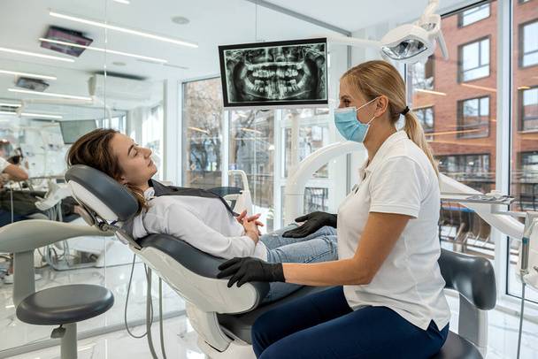 El dentista y el paciente eligen el tratamiento durante la consulta con el equipo médico en odontología. la solución adecuada para el tratamiento de la cavidad oral - Foto, imagen