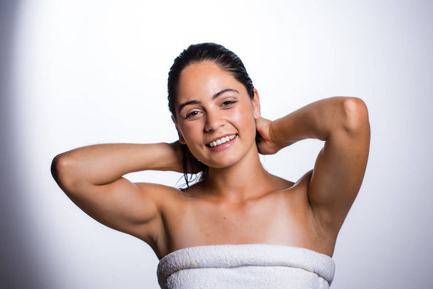 A stunning young woman takes care of her skin and beauty with a daily routine. Shot in a studio on a white background, her natural beauty radiates. - Foto, imagen