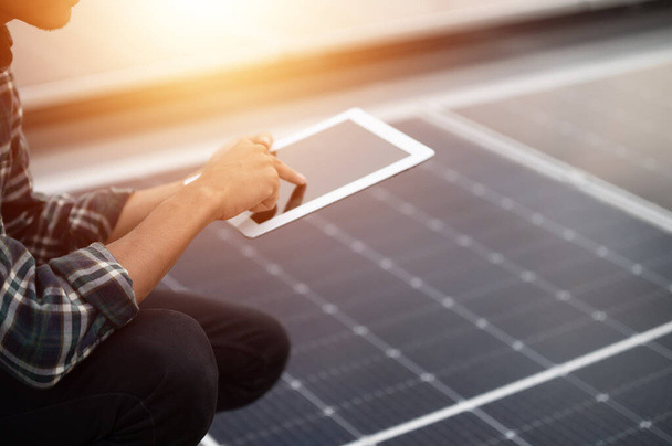 Ingeniero asiático que utiliza la comprobación de la tableta en el sistema de energía solar para la fábrica de techo superior de control ecológico industrial - Foto, imagen