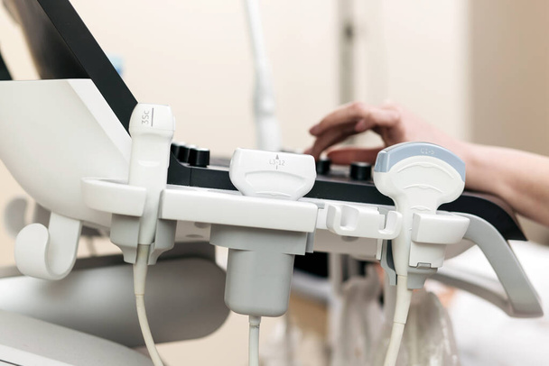 La mano del medico effettua una visita medica del paziente utilizzando uno scanner ad ultrasuoni. Primo piano di una macchina ad ultrasuoni e mano di un medico che ci lavora. Concetto - Foto, immagini