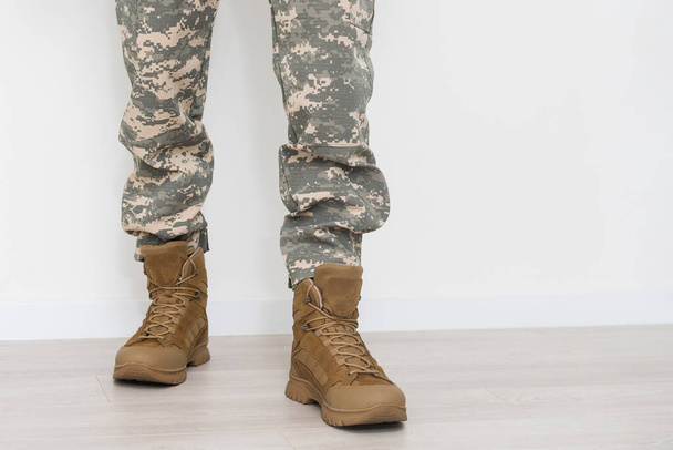 Egy álcázott katona lábai, szürke hátterű katonai bakancsban. Katonai konfliktusok és válságok. Közelkép. - Fotó, kép