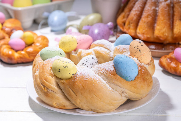 Húsvéti koszorú kenyér, hagyományos húsvéti ünnep sütés, édes zsemle sütemények színes húsvéti tojással, a villásreggeli ünnep díszített asztali másolási hely - Fotó, kép