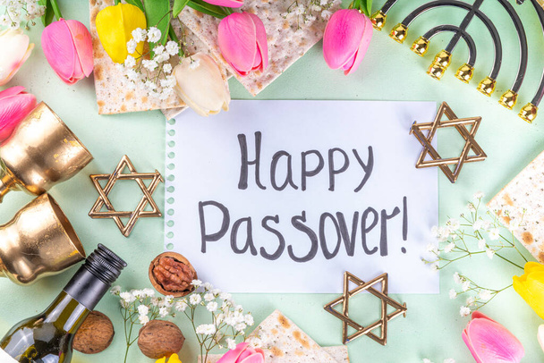 Passover, Pesah background. jewish Easter Passover spring holiday celebration, with accessories - menorah, matzo, spring flowers, wine bottle, gold wine glass, jewish david stars, copy space top view  - Photo, Image