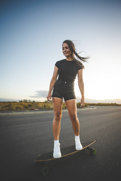 pretty young woman with dark hair skateboarding in a vibrant urban environment. - Fotó, kép