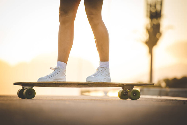 young woman with dark hair skateboarding in a vibrant urban environment. - Фото, зображення