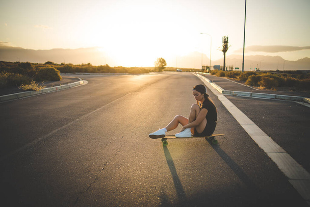 pretty young woman with dark hair skateboarding in a vibrant urban environment. - Photo, image