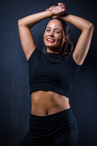 pretty dark haired girl posing for a fitness photo shoot in a studio. She is dressed in tight shorts and a crop top, and her poses convey a sense of strength, athleticism, and fitness.  - Foto, immagini