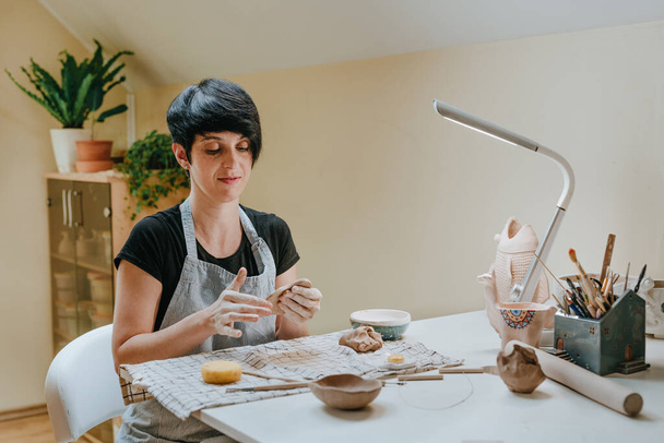 Jonge vrouw die met klei werkt in een keramistische werkplaats. Selectieve focus. - Foto, afbeelding