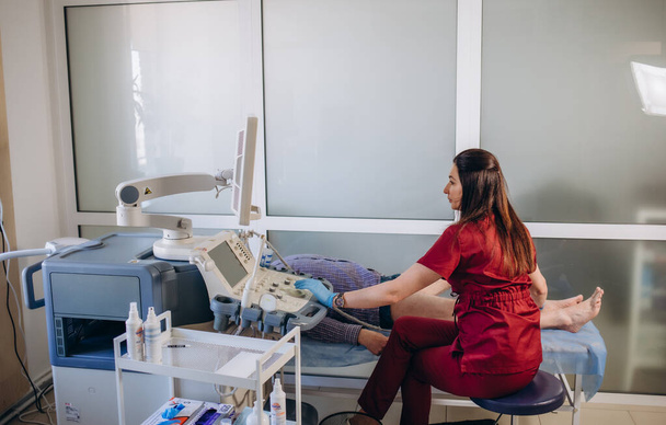 Ορθοπεδικός γιατρός κάνει υπερηχογράφημα εξέταση του γόνατος του ασθενούς στην κλινική - Φωτογραφία, εικόνα