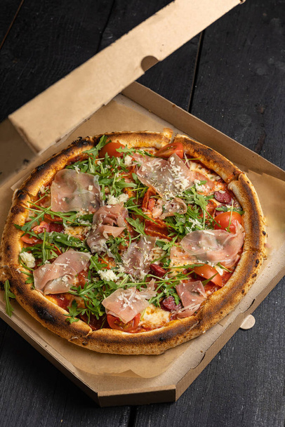 Delicious pizza with prosciutto, herbs and cheese. Food delivery - 写真・画像