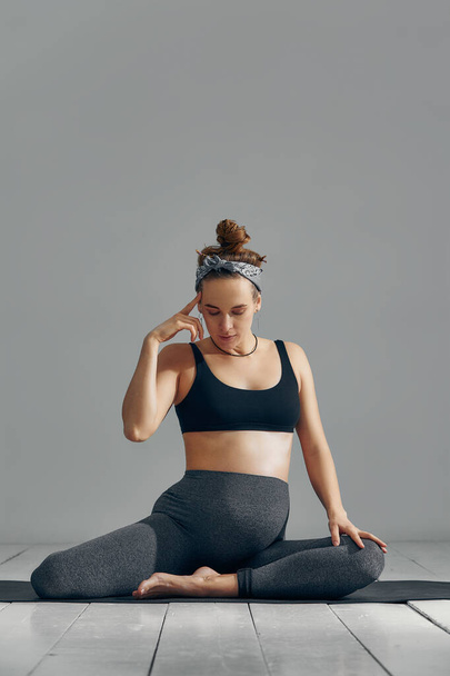 Schwangere streckt Arme und Beine, macht pränatales Training zu Hause auf der Yogamatte. Selektiver Fokus. - Foto, Bild