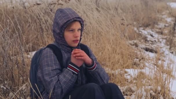 Caucasian boy teenager warm frozen hands. The child froze walking in nature in winter. Portrait of teenage boy closeup, warming his hands. - 映像、動画