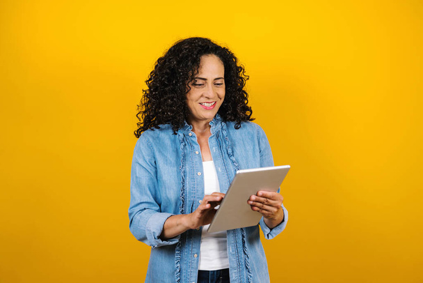 hispanic adult business senior woman portrait holding digital tablet on yellow background in Mexico Latin America - Foto, Imagem