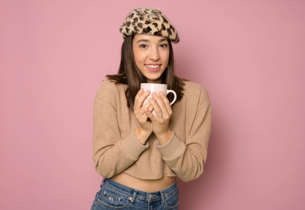 Young pretty woman poses with cup of coffee isolated on pink background - Φωτογραφία, εικόνα