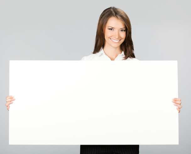 Businesswoman showing signboard, over grey - Foto, Imagen