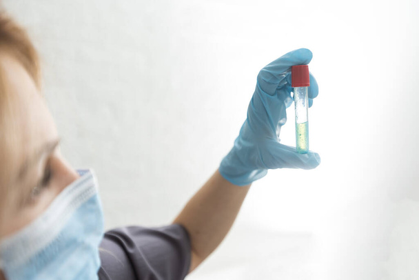 Biologische Gefährdung. Epidemie des chinesischen Coronavirus. Eine Frau in Schutzmaske hält eine Spritze und einen Impfstoff in der Hand. Grippe, Coronavirus, Ebola, TB - Foto, Bild