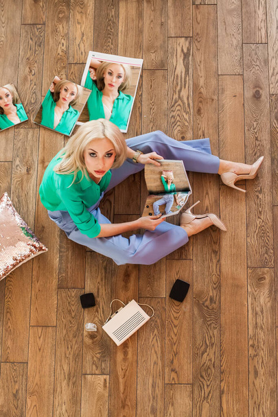 Блондинка в зеленой рубашке читает журнал и смотрит в камеру сверху - Фото, изображение
