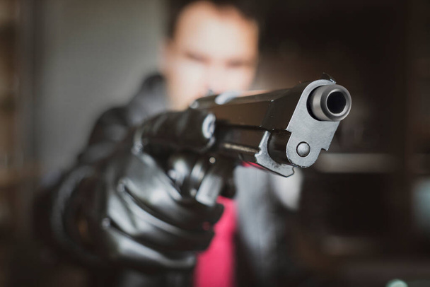 A man, policeman or robber, gangster concealing his gun. The shooter aims through the sight. Focus on the barrel of the gun. - Fotoğraf, Görsel