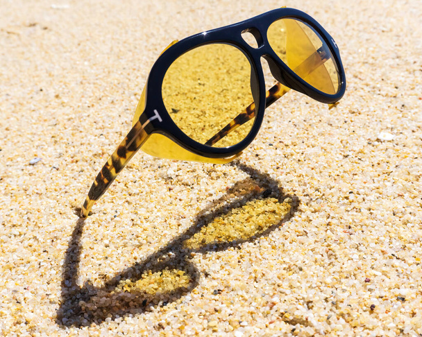 Niezwykłe żółte okulary utknęły w piasku na plaży z bliska - Zdjęcie, obraz