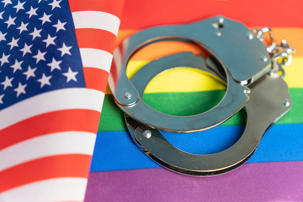 наручники, флаг США и флаг ЛГБТ. Проблема прав сексуальных меньшинств в стране. нетрадиционные отношения и политическая концепция. - Фото, изображение