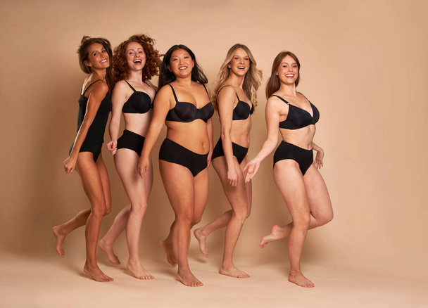 Skupina veselých žen v černém spodním prádle stojí a usmívá se směrem ke kameře - Fotografie, Obrázek