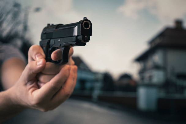 рука людини тримає вказівний пістолет з пальцем на спусковому гачку. концепція вуличної злочинності. чоловік грабує на вулиці. Загроза смерті
. - Фото, зображення