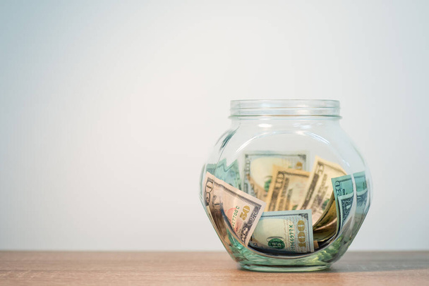 Glass jar with dollar money on the table. Concept of saving money to buy something - Zdjęcie, obraz