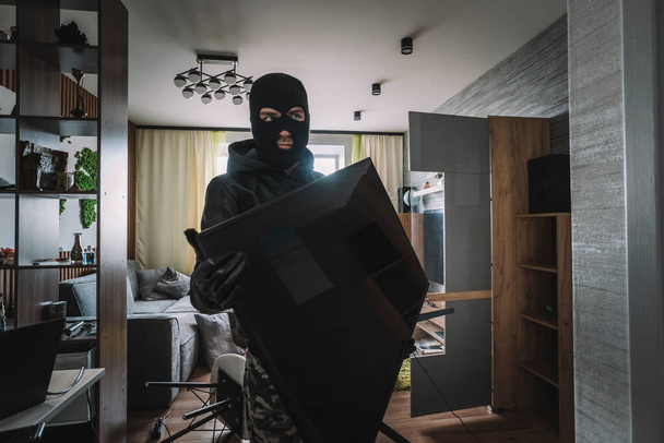 marauder takes the TV out of an empty apartment. Apartment theft concept. The burglar. - Fotó, kép