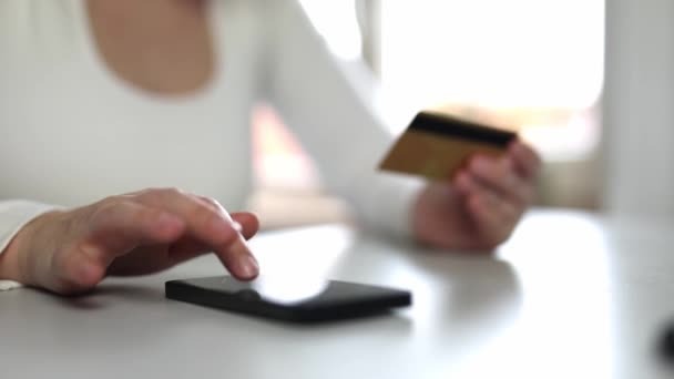 Vrouw met kredietkaart met behulp van instant mobiele betalingen thuis. Lachend mooi meisje klant shopper het maken van aankoop op de smartphone ontvangen cashback concept. E-banking app service close-up - Video