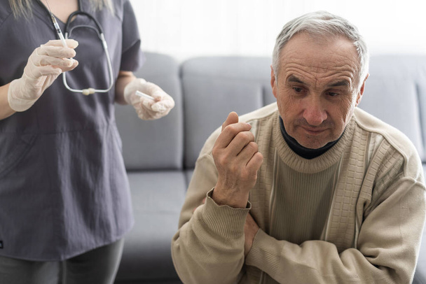 Doctor giving vaccination shot to elderly patient by syringe or injunction at home. concept of home health check to seniors during coronavirus covid-19 pandemic. - Zdjęcie, obraz