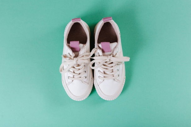 Kids white sneakers. Color background.  Fashion kids outfit. Children's clothes and accessories for spring, autumn or summer. Flatlay, top view. - Фото, изображение
