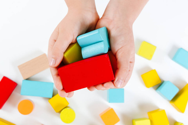 Child's hands playing with colorful wooden bricks. Wooden play set. Development and learning concept. Close-up view - Photo, image