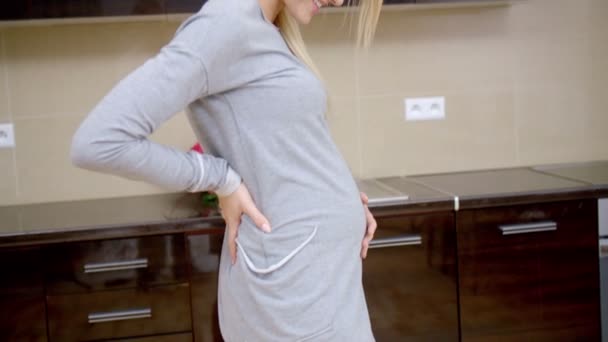Pregnant young woman standing in her kitchen - Video