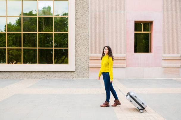 Šťastná mladá žena s kufrem s úsměvem a jít na služební cestu při chůzi na letiště ve městě - Fotografie, Obrázek
