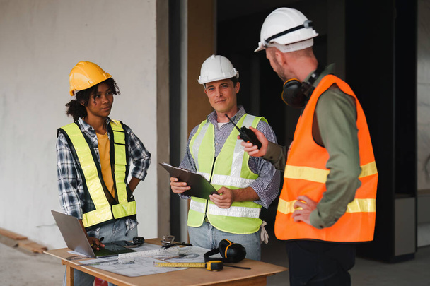 İnşaat alanında mühendis ve ustabaşı ekibi var. Amerikan Afrikalı ustabaşı inşaat sahasında duruyor. - Fotoğraf, Görsel
